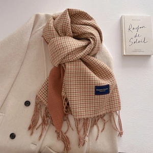 Detail of vintage houndstooth scarf with fringe edge and warm ginger knit texture