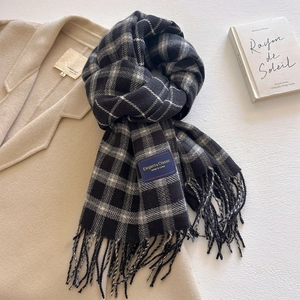 Detail of classic black and white plaid scarf with fringe on a beige wool coat