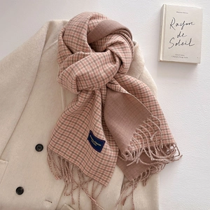 Detail of pink and brown houndstooth scarf with fringe and label on white coat