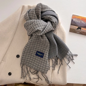 Detail of double-sided houndstooth scarf with elegant fringes on a wool coat