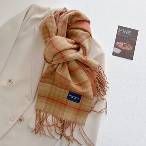 Detailed close-up of warm plaid tassel scarf with soft texture and brand label