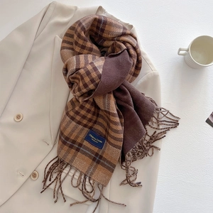 Detail of soft brown plaid scarf texture with fringe on a beige blazer background