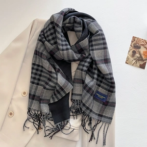Detail of grey and black plaid cashmere scarf with fringes on beige blazer