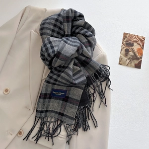 Detail of grey plaid cashmere-feel scarf with red accents and fringe on a white blazer
