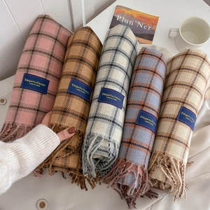 Five assorted soft plaid scarves with fringe and elegant labels on white surface