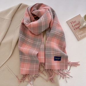 Detail of pink and grey plaid scarf with tassels on a wool coat with lifestyle props