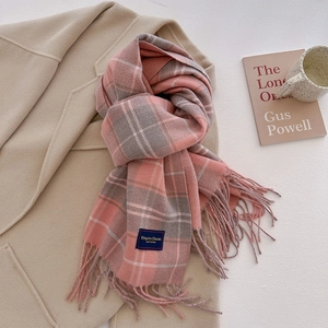 Close-up of pink and grey plaid scarf with soft fringe and elegant classic fabric label