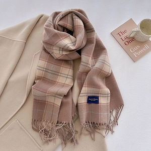 Close-up of classic plaid scarf texture with elegant woven label and soft fringe details