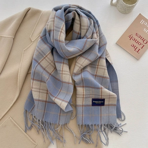 Detail of light blue and beige plaid scarf with tassels on a wool coat background