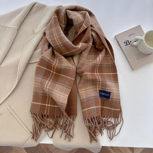 Close-up of brown plaid scarf with fringe details and elegant classic woven label