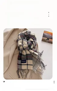 Detail of plaid scarf with fringe and brand label on a classic beige woolen coat