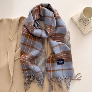 Detail of soft plaid scarf with tassels and elegant blue label on woolen coat