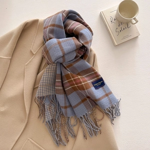 Detail view of plaid cashmere feel scarf with fringe on wool coat and coffee