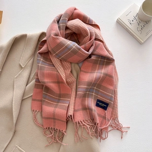 Close-up of a pink plaid cashmere scarf with soft tassels and elegant woven label
