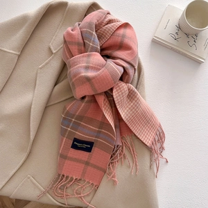 Detail of pink plaid cashmere-feel scarf with tassels on wool coat background