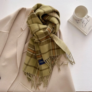 Detail of green and brown plaid cashmere-feel scarf with elegant fringe on a coat