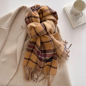 Detail of cashmere-like plaid scarf with tassels styled on a camel wool coat