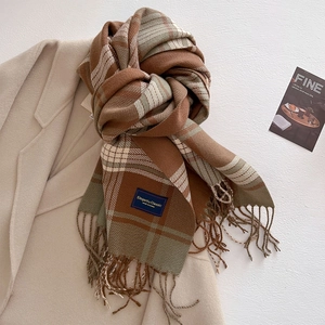 Close-up of thick plaid scarf texture with handmade tassels and woven brand label