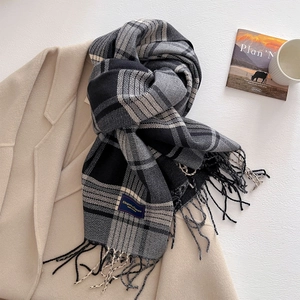 Flat lay of plaid tassel scarf on beige coat with coffee cup and magazine accents