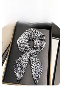 Detail of a 70cm square scarf with leopard print folded in a bow on a luxury tray