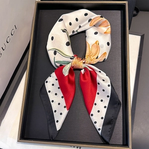 Detail of silk-feel scarf with black-white polka dots and vibrant orange floral patterns