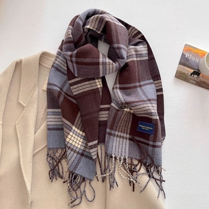 Detail of plaid cashmere-like scarf showing soft fringe and elegant classic label weave