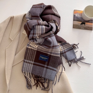 Classic plaid scarf detail with elegant blue label and long fringes on beige coat