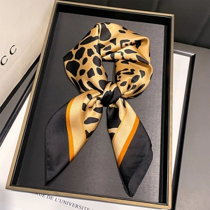 Detail of leopard print silk scarf with black and orange borders on a black tray