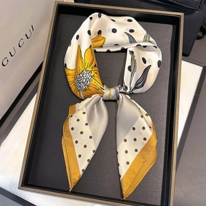 Detail of silk scarf showing sunflower floral print and polka dots tied in a bow