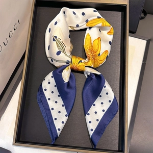 Detail of faux silk scarf featuring sunflower patterns and navy blue polka dots in a bow knot
