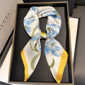 Detail of silk-like twilly scarf with blue tulip floral prints and yellow edges