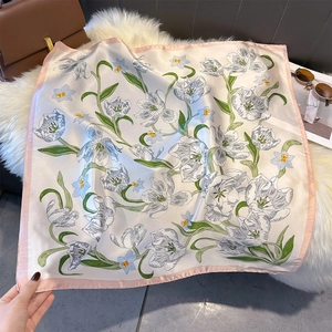 Close-up of silk-textured square scarf with tulip floral prints on soft white rug