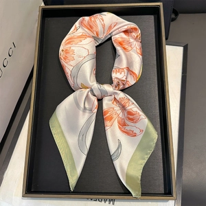 Detailed view of white silk scarf with orange tulips in a black luxury gift box