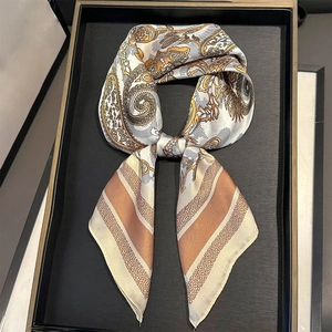 Detail of silk-like square scarf featuring paisley pattern and gold-tone striped borders