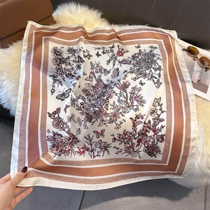 Detail of silk-like square scarf featuring elegant floral butterfly patterns and geometric borders