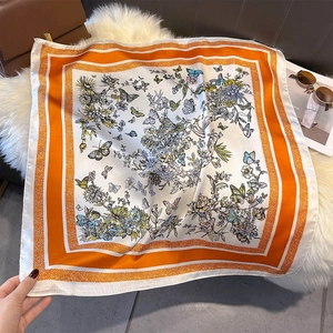 Detailed pattern of butterfly and flowers on a white silk scarf with orange borders