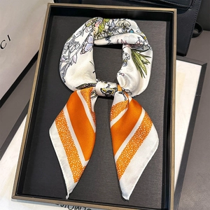 Detailed view of square silk scarf with purple butterfly patterns and orange trim