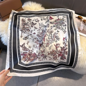 Detail of silk-like square scarf featuring elegant floral patterns and butterfly prints