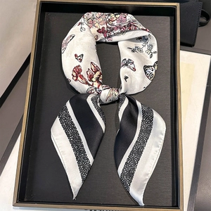 Detailed view of patterned silk scarf with floral motifs and geometric stripes tied in a knot