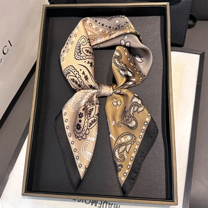 Detail of folded paisley silk-like square scarf with elegant black border on a tray