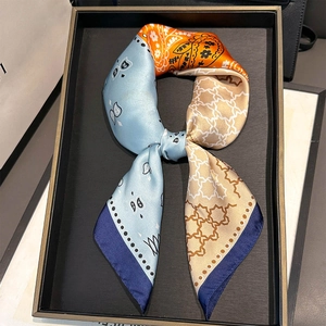 Close-up of silk scarf with paisley and star patterns tied in a bow on a black tray