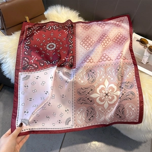 Detailed view of paisley silk square scarf with geometric burgundy and pink patterns