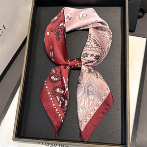 Detail of silk-like neck scarf featuring burgundy paisley patterns and Eiffel Tower design