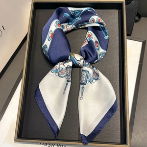 Detail view of silk-texture square scarf with blue illustrated patterns in a bow shape