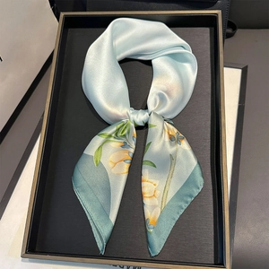 Detail of light blue silk scarf with floral print on a minimalist black display tray