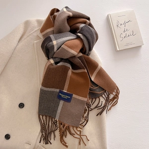 Detail of plaid cashmere-like scarf with hand-knotted tassels and soft checkered texture