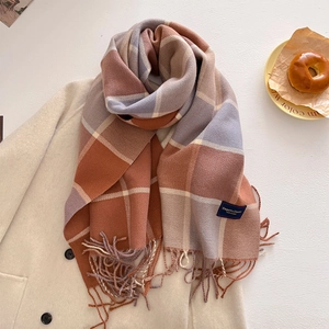 Macro shot of thick checkered scarf with tassels draped over a beige coat