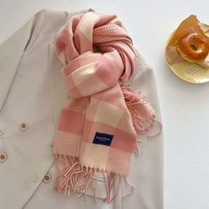 Detailaufnahme des rosa-beigen Kaschmirschals mit Fransen auf einem beigen Blazer