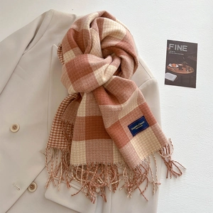 Detail eines karierten Kaschmirschals mit Fransen und Etikett auf beigem Blazer