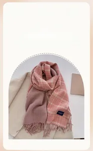 Detailed view of pink plaid scarf with fringe on beige coat in a cozy autumn setting
